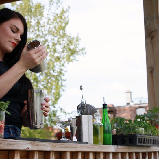 HOSPITALITY BARTENDER ALLISON EVERITT SHAKING A COCKTAIL ON THE FRONT PORCH OF HER DETROIT HOME