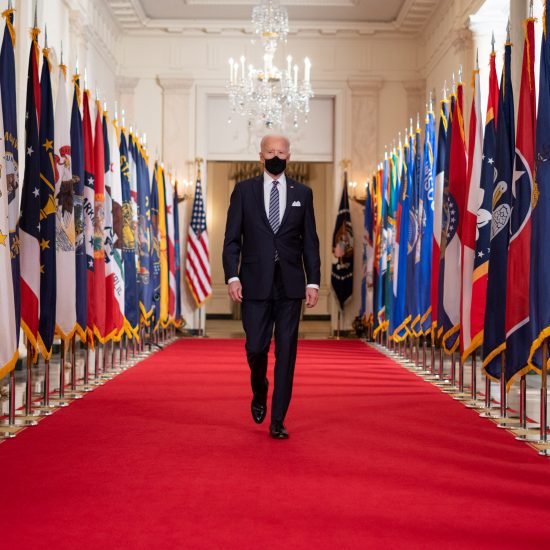 how do you rate biden's first 100 days? // biden walking down a hall with a mask // PRESIDENT JOE BIDEN BEFORE DELIVERING COVID-19 REMARKS ON MARCH 11, 2021. OFFICIAL WHITE HOUSE PHOTO BY ADAM SCHULTZ