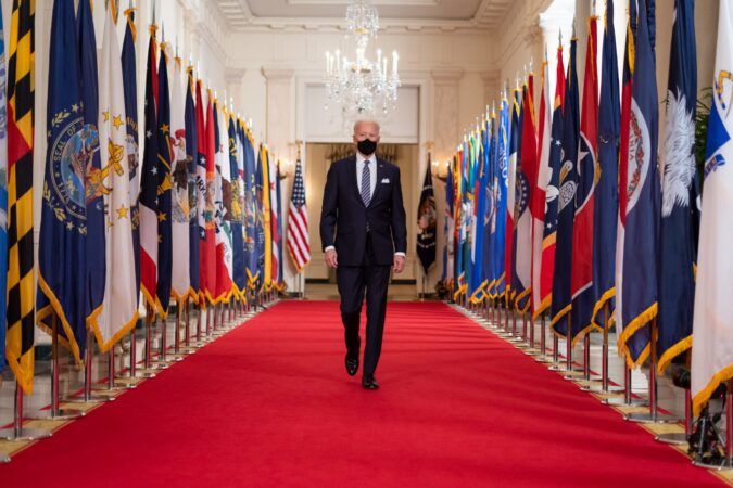 how do you rate biden's first 100 days? // biden walking down a hall with a mask // PRESIDENT JOE BIDEN BEFORE DELIVERING COVID-19 REMARKS ON MARCH 11, 2021. OFFICIAL WHITE HOUSE PHOTO BY ADAM SCHULTZ