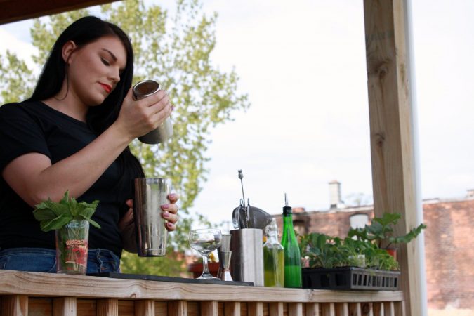 HOSPITALITY BARTENDER ALLISON EVERITT SHAKING A COCKTAIL ON THE FRONT PORCH OF HER DETROIT HOME
